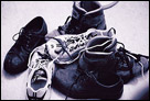 This is a black and white photo close up of a pile of shoes and sneakers.