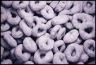 This is a black and white photo close up with a macro lense of a bowl of Cheerios cereal.