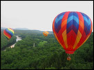 This is a color photograph of some beautiful hot air balloons flying over Greenfield, Massachusetts.